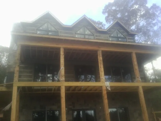 Dormers and porch framing on a large log home under construction — Roof Coating work by our crew in Casa Blanca