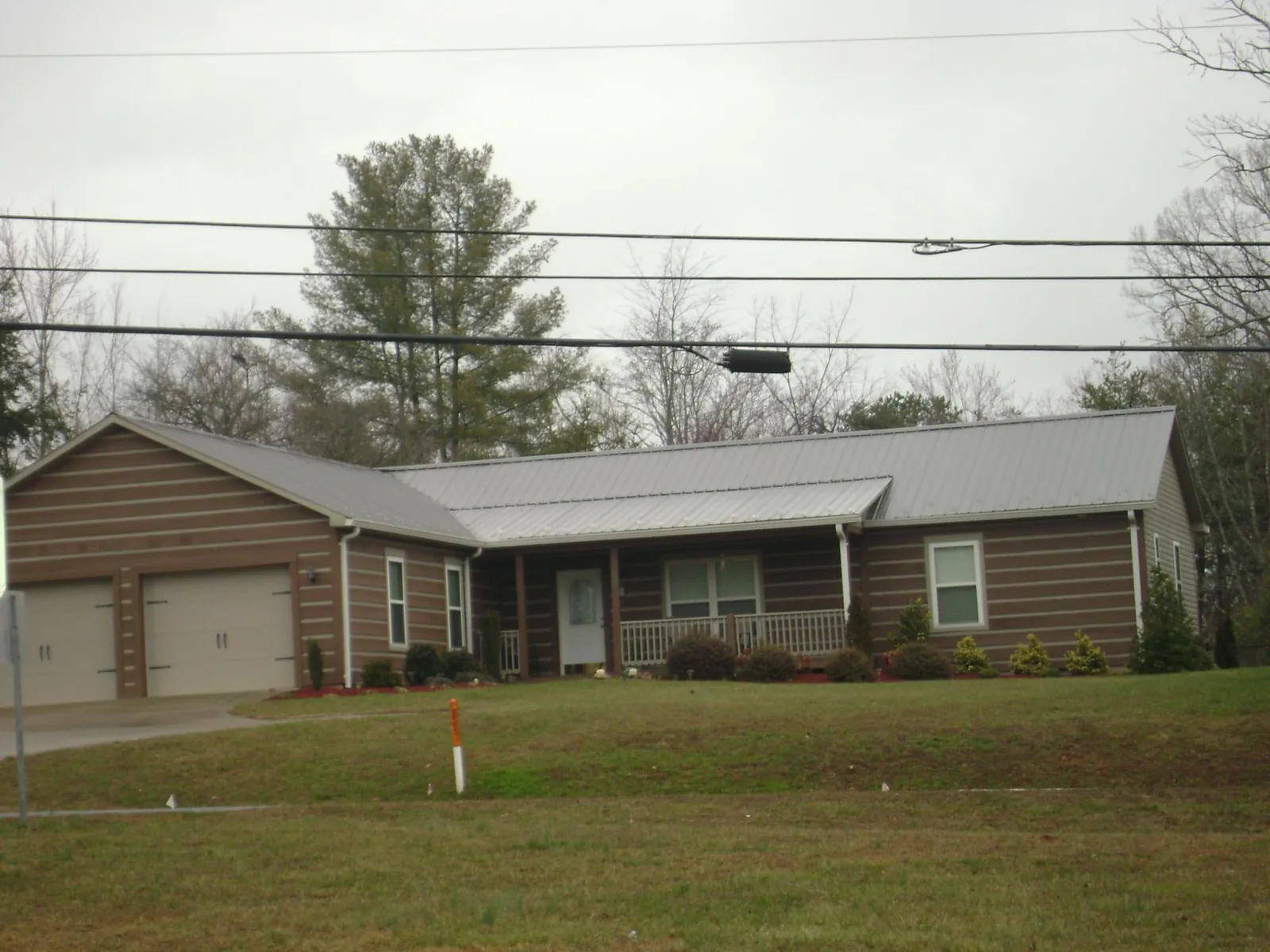 Gray metal roof on a log sided ranch home with a front porch in Casa Blanca