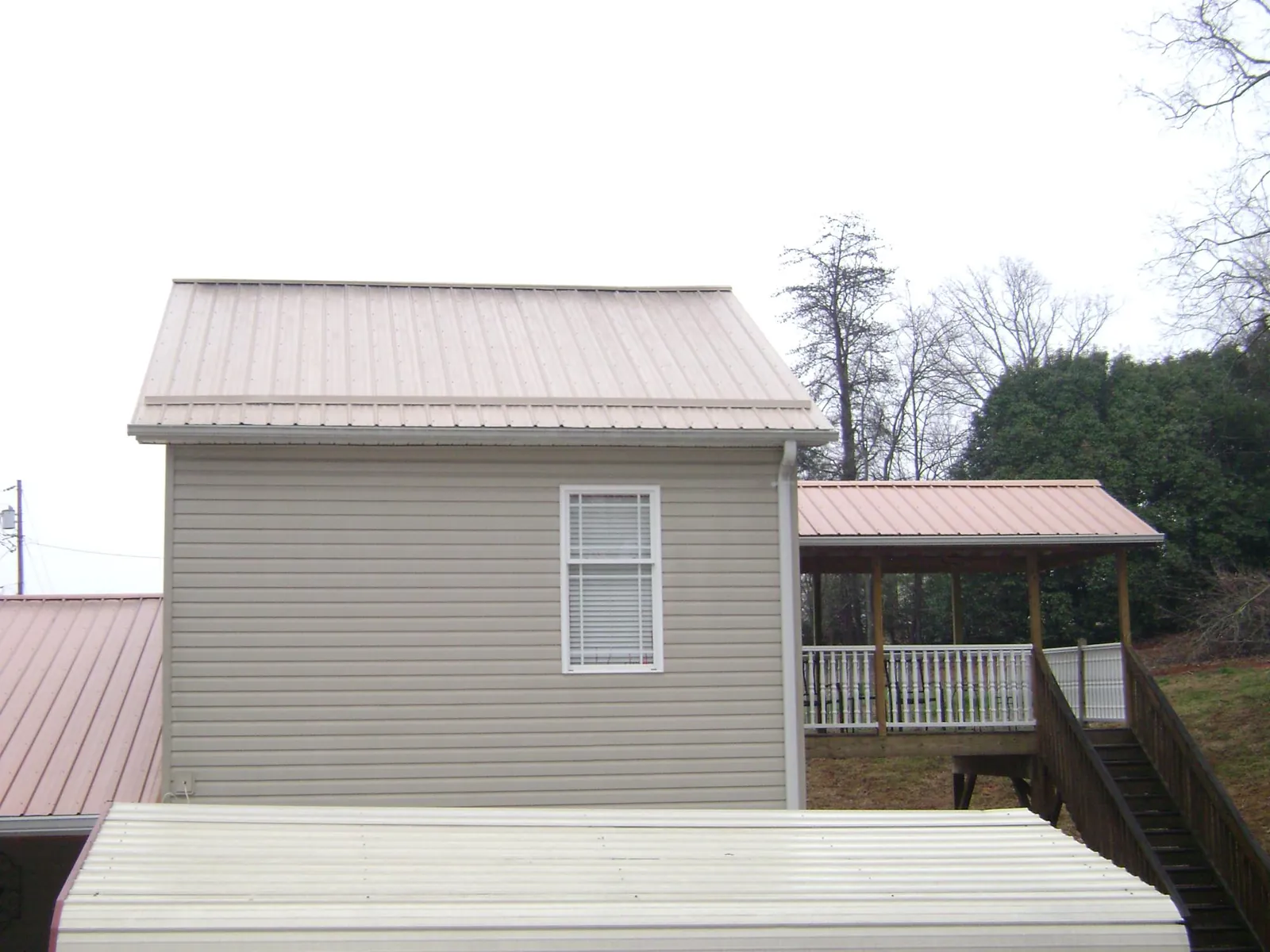 Tan metal roofs on a two story addition and attached porch, from a Roof Replacement job in Casa Blanca