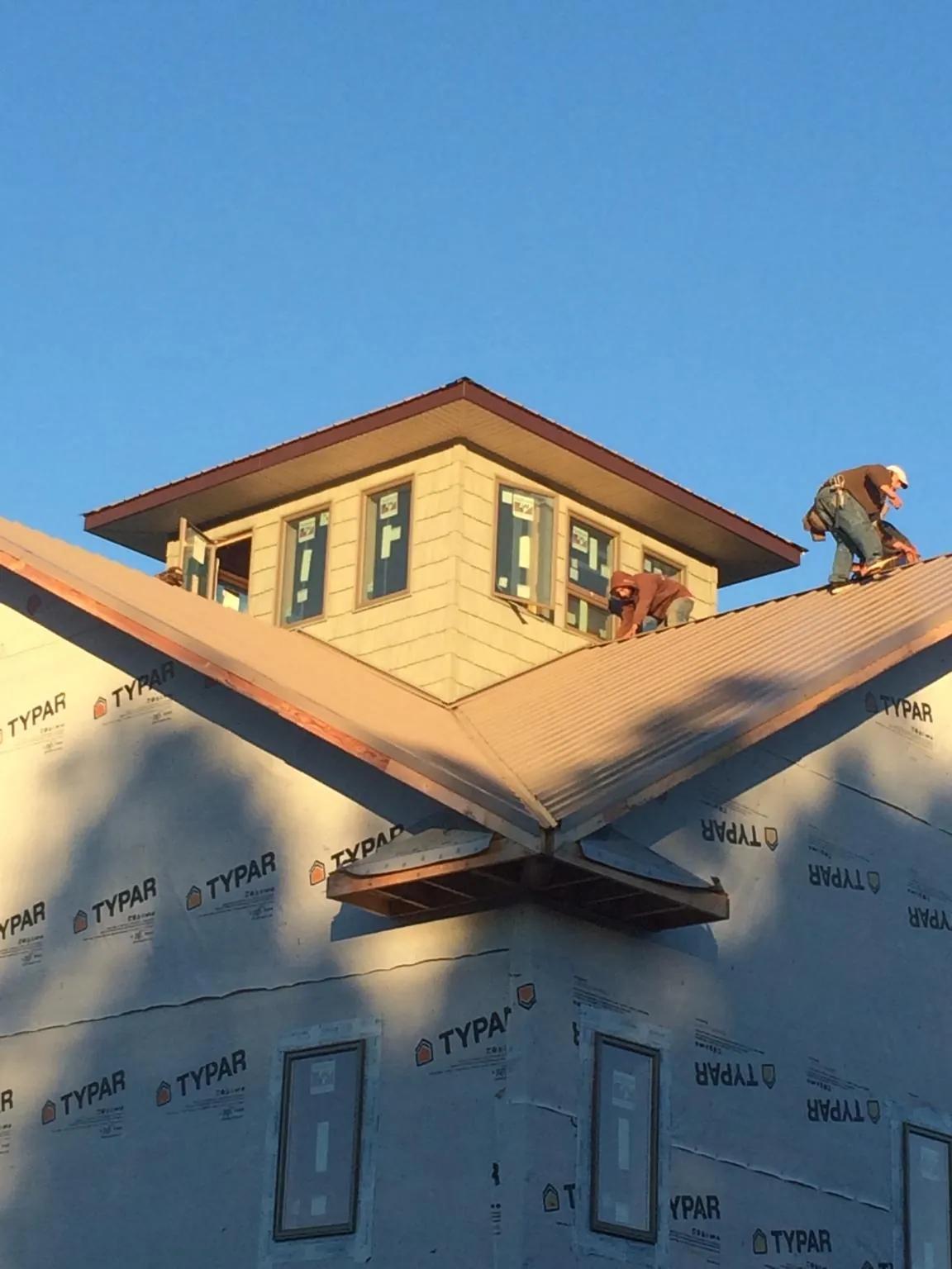 Roofers working around a rooftop cupola on a new metal roof at sunset — Roof Waterproofing in Casa Blanca by Roofing Brothers